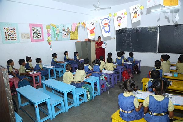 Focus on students writing diligently in their notebooks during a classroom lesson at SBVR School, Avadi.