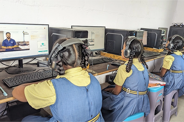 Students learning computer skills in SBVR School's modern technology lab with desktop workstations